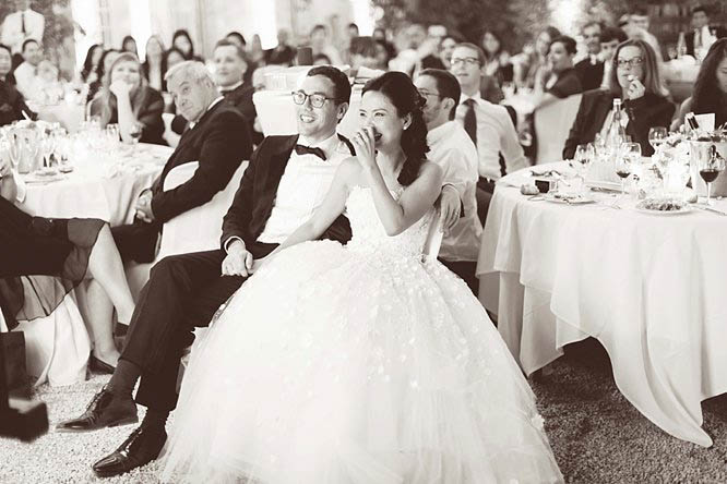 reportage black and white photo of bride and groom laughing during best mans speech