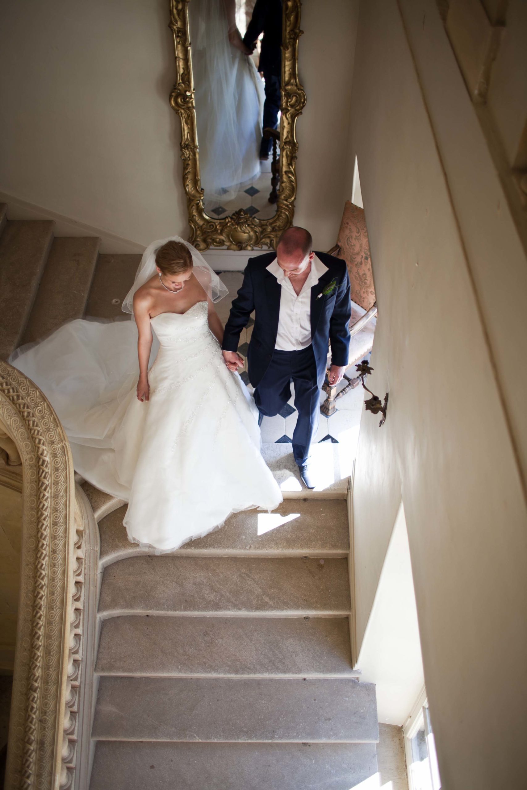 Married couple descending stairs of a chateau after their French wedding