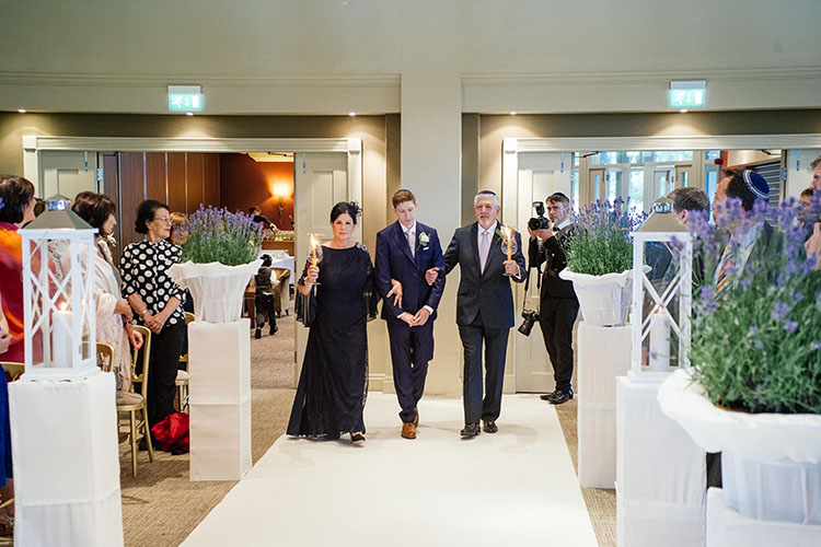 groom walking to the chuppah with his parents